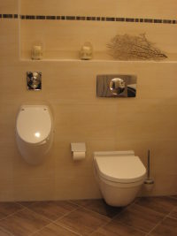 Urinal und WC in weiß an sandfarben gefliester Wand, Bodenfliesen braun meliert